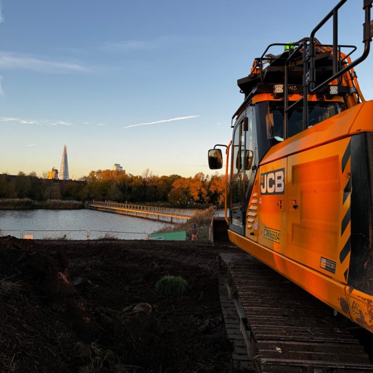 Excavator carrying out bulk earthmoving and ground regrading works on a live construction site using digger hire 