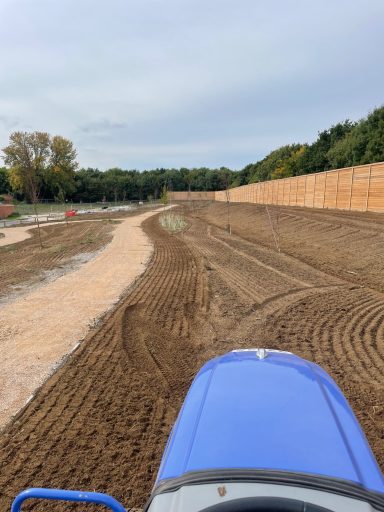 Tractor preparing and conditioning soil for seed bed works on new build site in Sittingbourne